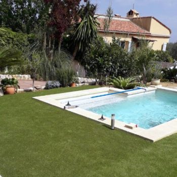 piscine_turquoise_bordée_de_gazon_en_plaque_dans_le_jardin_dune_maison_type_provencal